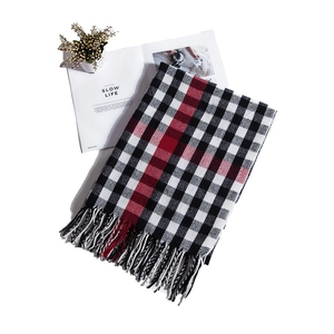 Detailed view of red and black plaid scarf with fringe on a white minimalist setting