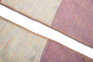 Macro shot of striped faux cashmere shawl featuring a purple weave and handmade overlock edges