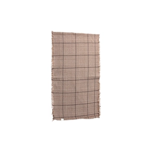 Detail of brown plaid scarf showing classic checkered pattern and fringe hem with care label