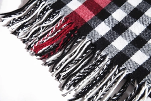 Close-up detail of soft plaid scarf fabric with red white and black fringe texture