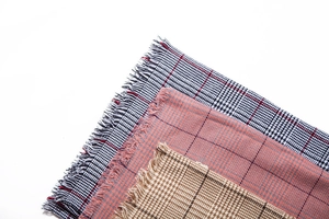 Close-up of fringe details on classic plaid cashmere-feel scarves in multiple colors