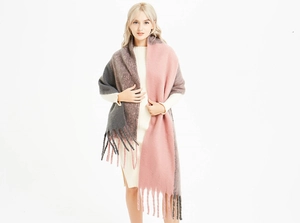 Détail d'une écharpe en maille épaisse rose et gris foncé avec de longs pompons