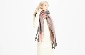 Gros plan d'une écharpe en maille épaisse bicolore gris et rose avec longues franges