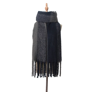 Détail de franges à pompons sur une écharpe en maille épaisse bicolore gris et bleu