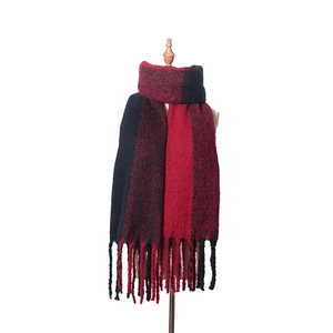 Gros plan d'une écharpe en maille bicolore rouge et noire avec de longues franges