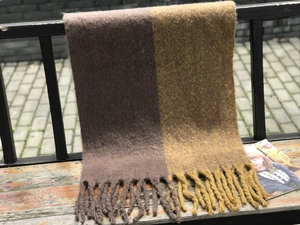 Détail d'une écharpe en maille épaisse avec blocs de couleur marron, jaune et franges