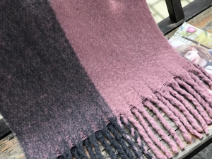 Détail d'une écharpe en maille bicolore grise et rose avec de longues franges déco