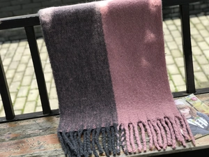 Détail de l'écharpe bicolore gris et rose avec de larges franges sur un banc en bois