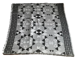 Detail of geometric knit scarf with tribal patterns and decorative fringe edges