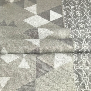 Close-up of thick knitted geometric jacquard patterns on soft grey cashmere-style shawl