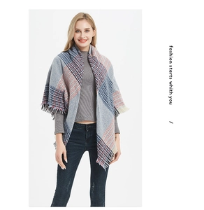 Détail d'une grosse écharpe à carreaux bleu et rouge avec franges sur pull gris