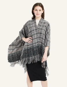 Close-up of thick bouclé plaid scarf featuring fringe hem and warm knit texture