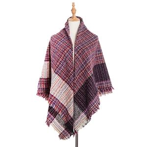 Close-up of thick checkered knit shawl featuring colorful tassels and woven texture