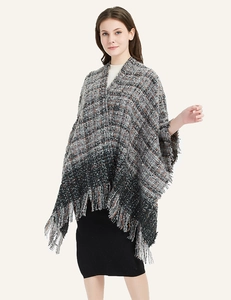 Close-up of thick plaid knit shawl featuring orange and black stripes with fringe trim