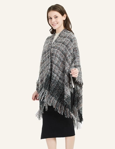 Detail of chunky knit plaid shawl with thick fringe hem and warm textured fabric