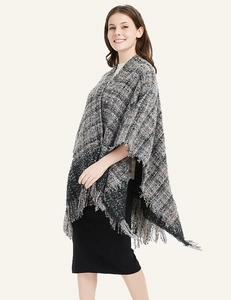 Detail of plaid knit poncho featuring fringe hem and classic checkered pattern