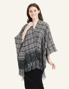 Detailed view of bouclé knit texture and fringe edge on a thick checkered winter shawl