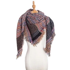 Close-up of thick plaid knit scarf texture with natural fringe detail on a white mannequin