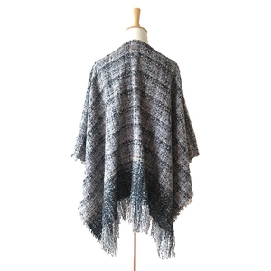 Detailed view of thick boucle plaid shawl with fringe hem on a professional mannequin