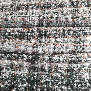 Close-up of textured bouclé plaid fabric showing grey and orange woven patterns
