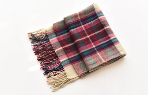 Detailed view of woven tassels and classic red blue plaid pattern on warm winter scarf