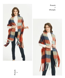 Detail of colorful plaid scarf with fringes featuring red, orange and blue grid patterns