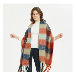 Detail of oversized thick plaid scarf featuring vibrant orange and navy checks with long tassels