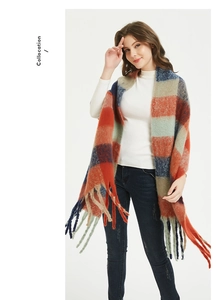 Detail of winter oversized plaid scarf featuring orange and navy block patterns with fringe