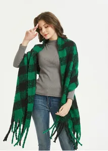 Macro view of thick green and black plaid knit shawl with decorative fringe detail