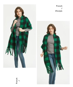 Detail of green and black buffalo plaid scarf with long fringe and soft knit texture