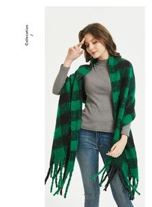 Close-up of green and black plaid scarf with thick fringe and soft textured fabric