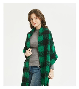 Detail of green and black checkered pattern on a thick knit scarf with fringed edges