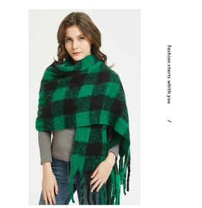 Close-up of thick green and black plaid scarf featuring soft brushed texture and long tassels