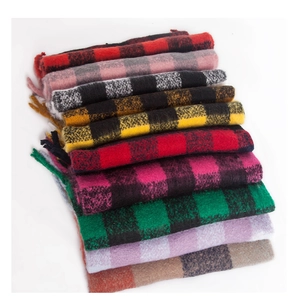 Detailed stack of thick plaid knit scarves with fringed edges in various color patterns