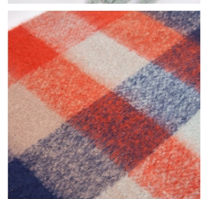 Macro shot of thick wool blend fabric showing vibrant orange and navy blue checkered texture