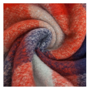 Detail of chunky knit scarf showing red and blue plaid texture and soft fuzzy fiber
