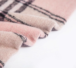 Close-up of soft plaid scarf fabric showing fuzzy pink and grey checkered wool texture
