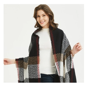 Close-up of thick plaid shawl with red and black tassels and soft wool-like texture