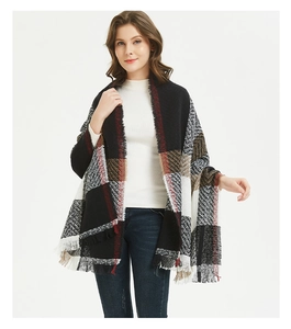 Detail of classic plaid scarf featuring red and black tartan pattern with fringe edge