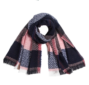Macro detail of plaid knit scarf featuring fringe edges and woven herringbone texture