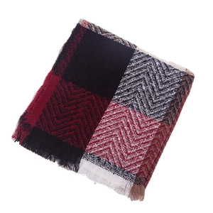 Detail showing the herringbone weave texture and soft tassel edges of the plaid scarf