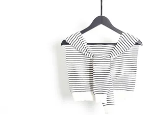 Detail view of a knitted striped shawl cape with ribbed edges on a wooden hanger