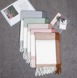 Close-up of stacked cashmere-like color-block scarves with fringe tassels and soft texture
