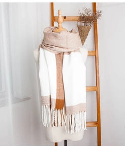 Detail of color-block plaid scarf with tassels on a white mannequin in a cozy setting