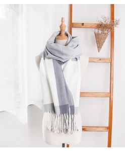 Detail of grey and white plaid cashmere-like scarf with fringe on a mannequin