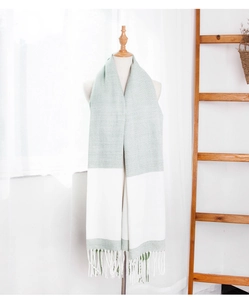 Detail of color-block scarf in sage green and white with delicate fringe tassels