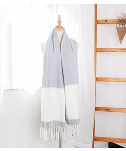 Detail of color-block knit scarf with grey and white segments and white fringe trim