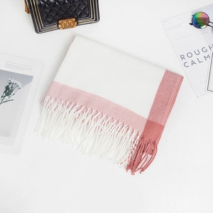 Detailed flat lay of a soft pink striped cashmere shawl with fringe trim on magazine