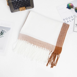 Detailed view of bicolor brown and white knit scarf with long decorative fringe tassels