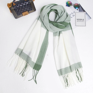 Detailed flat lay of green and white color-block plaid scarf with decorative tassels